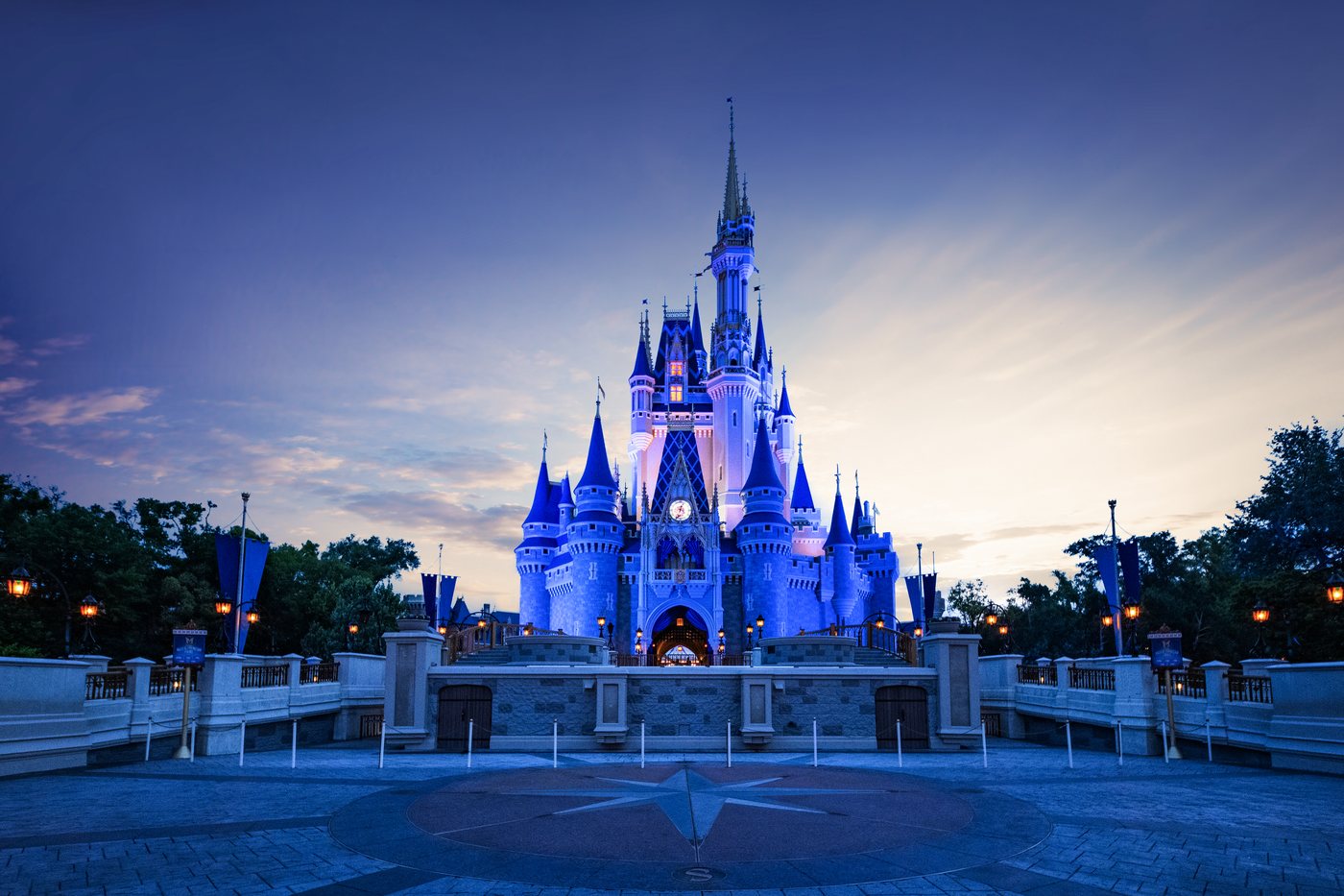 Cinderella Castle lit in blue at dusk, seen across the plaza at Magic Kingdom Park.