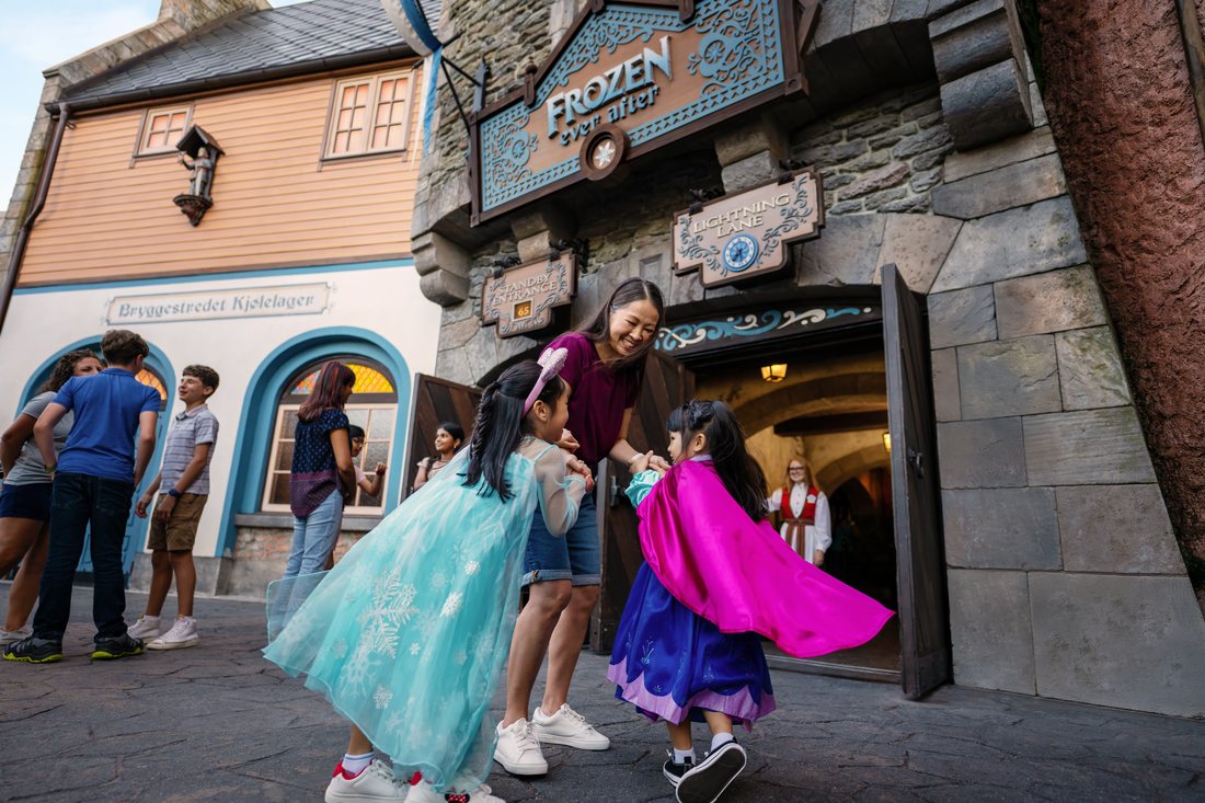 Two girls in princess dresses twirling outside Frozen Ever After at EPCOT.