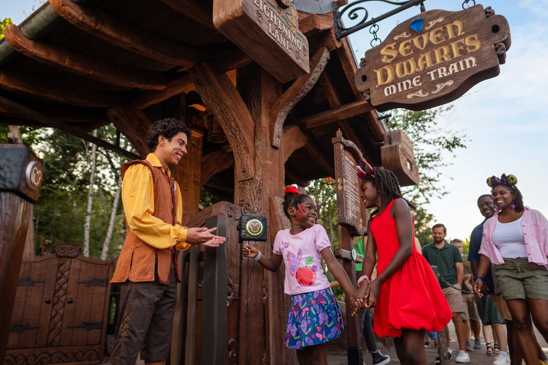 A family heading into Seven Dwarfs Mine Train with a Cast Member at Magic Kingdom Park.