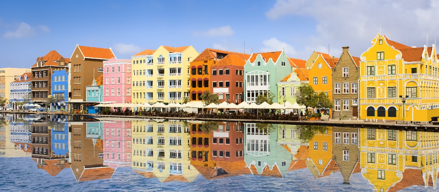 The colorful waterfront of Willemstad, Curaçao, across turquoise water.