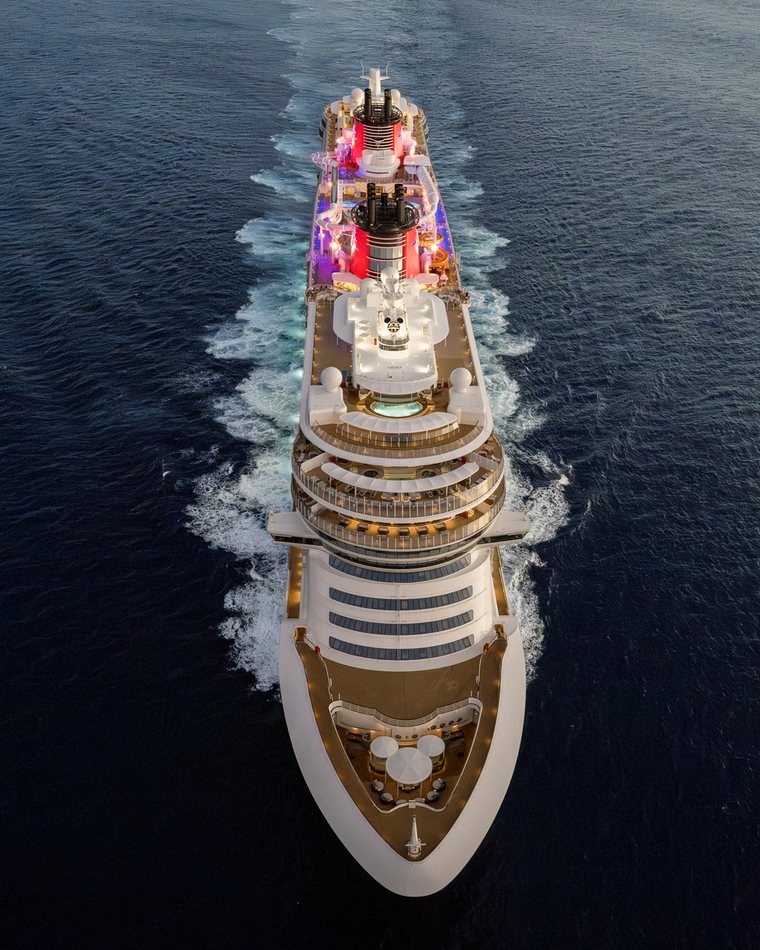 The Disney Treasure seen from above, sailing across deep blue water.