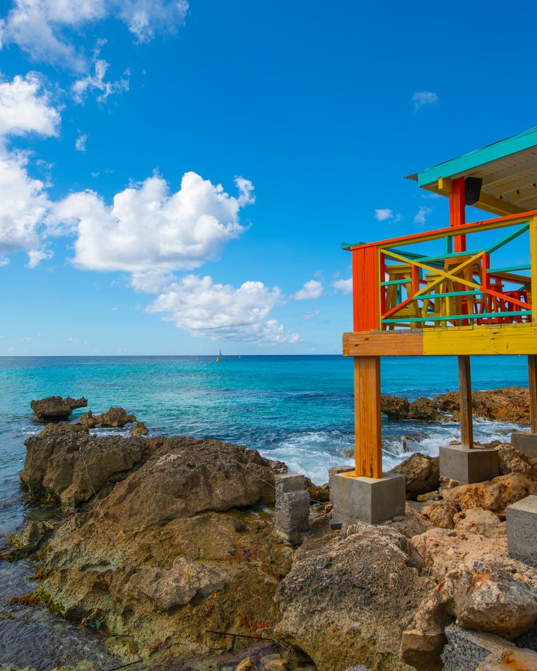 A colorful lifeguard stand above turquoise water.