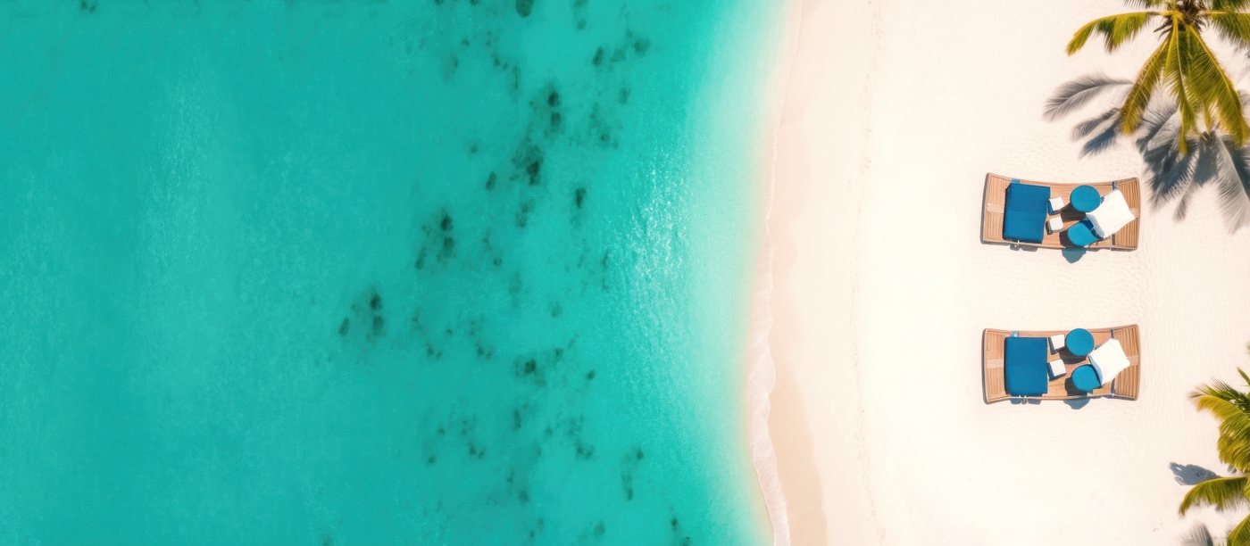 Turquoise shallows meeting pale sand, seen from above.