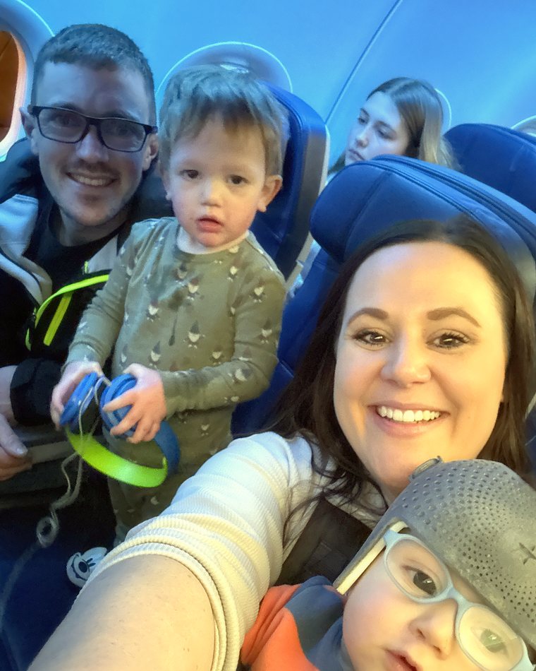 Cydnie taking a selfie on a plane with her husband and both boys.