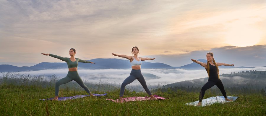 Three women holding a yoga pose at sunrise.
