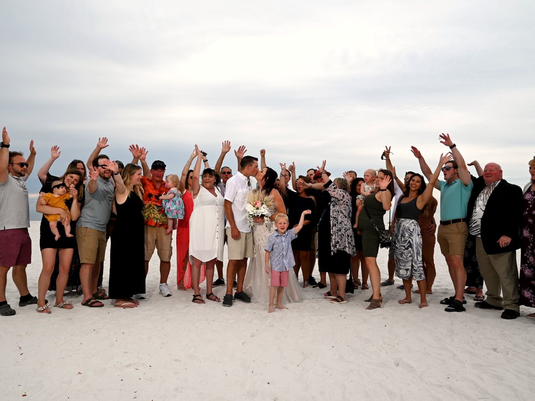 Cydnie's wedding guests cheering on a white sand beach.