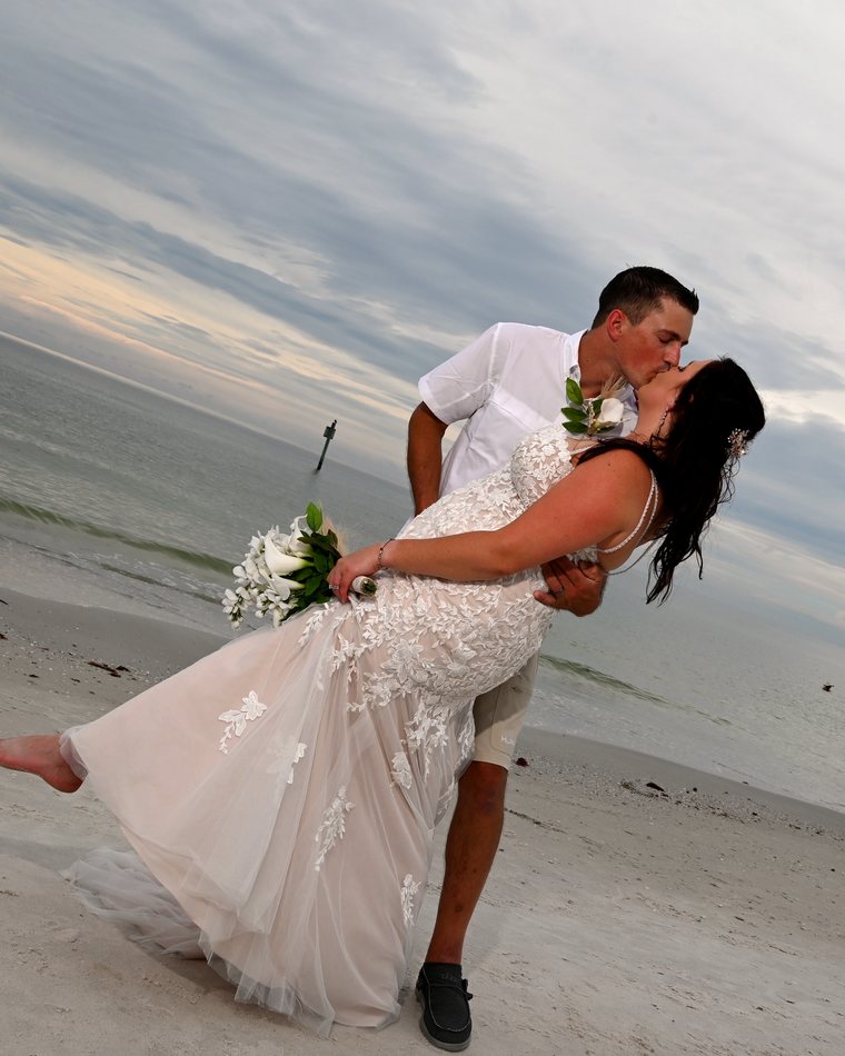 Cydnie and her husband kissing on the beach after their wedding.